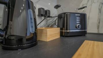 Een keukentafel met een koffiezetapparaat en een broodrooster.