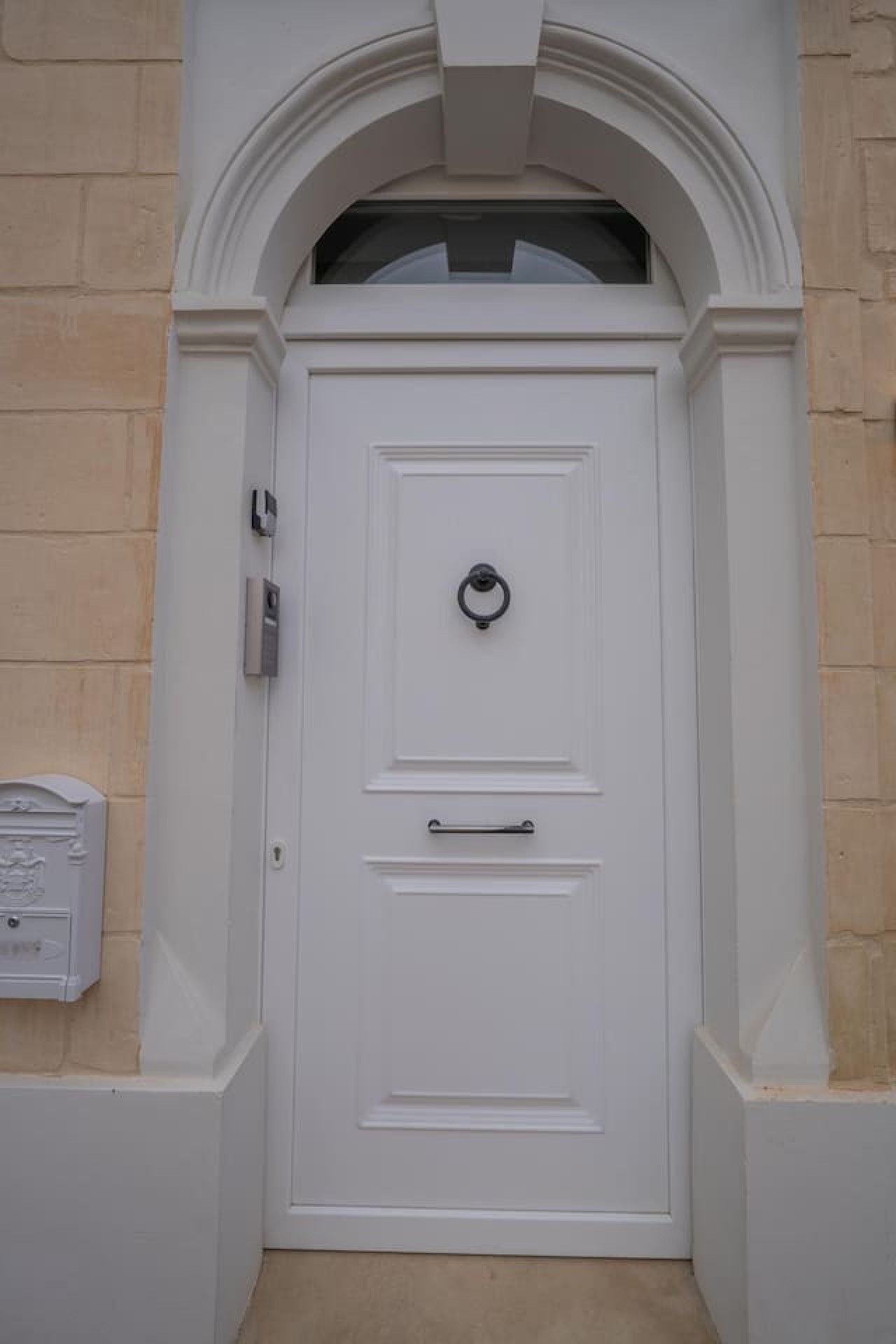 A white door with a knocker, a mail slot, and a handle.