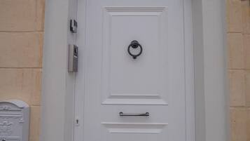 A white door with a knocker, a mail slot, and a handle.