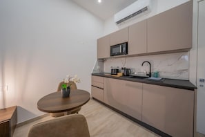 Una cocina moderna con microondas integrado, un lavamanos y una cafetera.