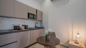 Eine kleine Küche mit Mikrowelle, Toaster und Spüle. Ein Esstisch mit Stühlen und ein kleiner Topfpflanze sind ebenfalls vorhanden.