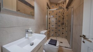 Ein modernes Badezimmer mit einem weißen Waschbecken, einer Toilette und einer Duschkabine.