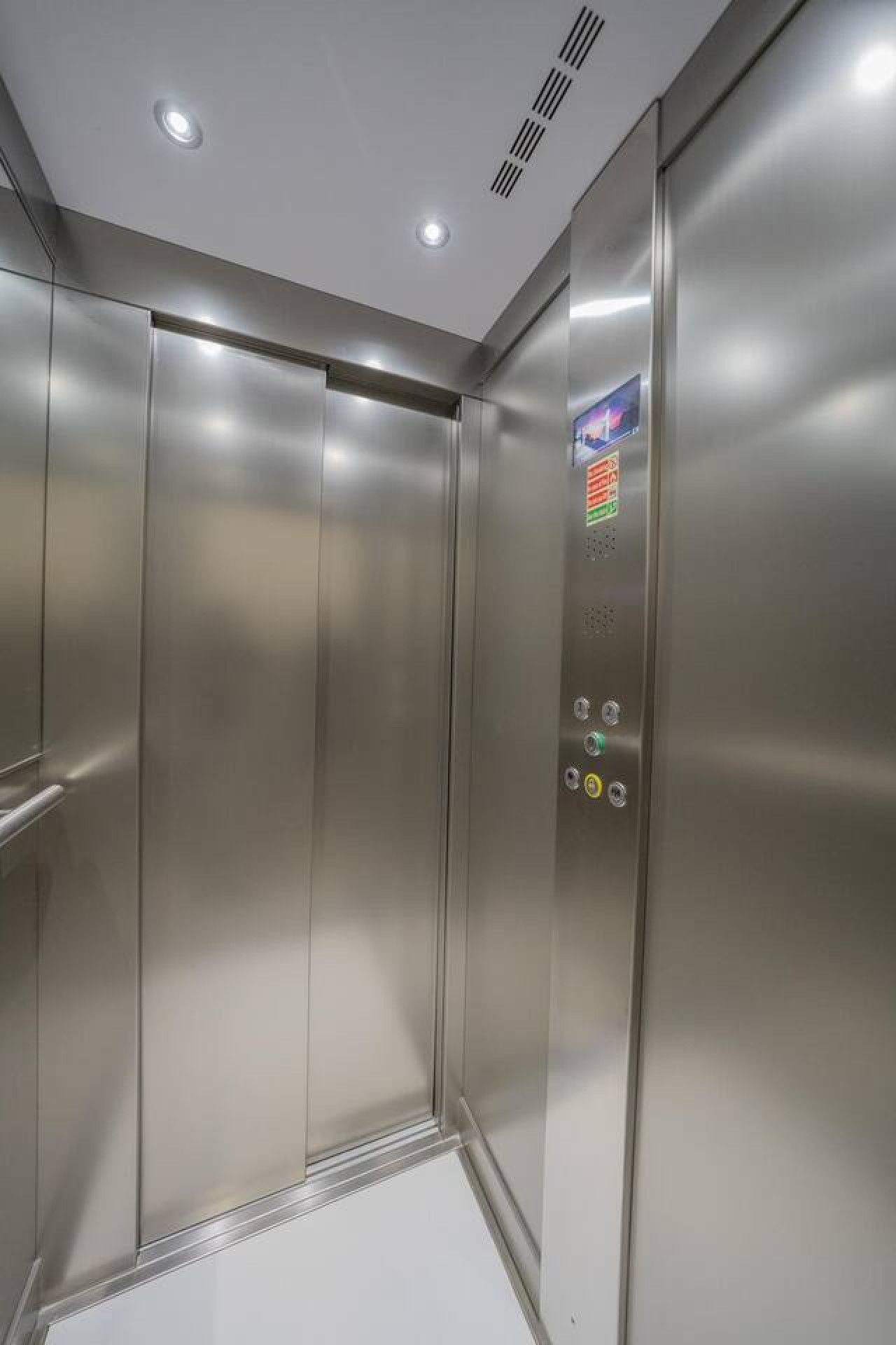Un ascensore moderno con pareti metalliche e un pannello di controllo con pulsanti.