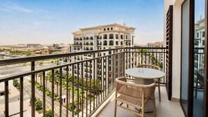 A balcony with a table and chair, overlooking a road and buildings. - Vanilla Homes Premium 1BR Yas Island (Abu Dhabi)