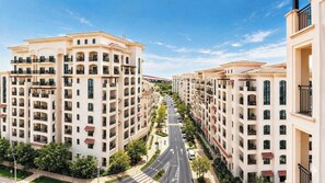 A multi-story residential building with balconies, a central road, and greenery. - Vanilla Homes Premium 1BR Yas Island (Abu Dhabi)
