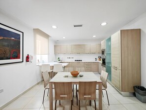 A modern kitchen with a dining table, chairs, and cabinets. - Good Times apartment (Sliema)