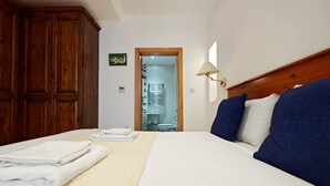Ein Hotelzimmer mit Bett, Holzschrank, offenem Badezimmer und Wandlampe.