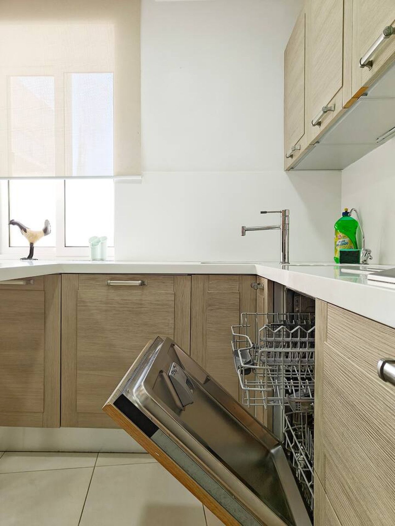 A kitchen with wooden cabinets, a dishwasher, and a window with a decorative item.