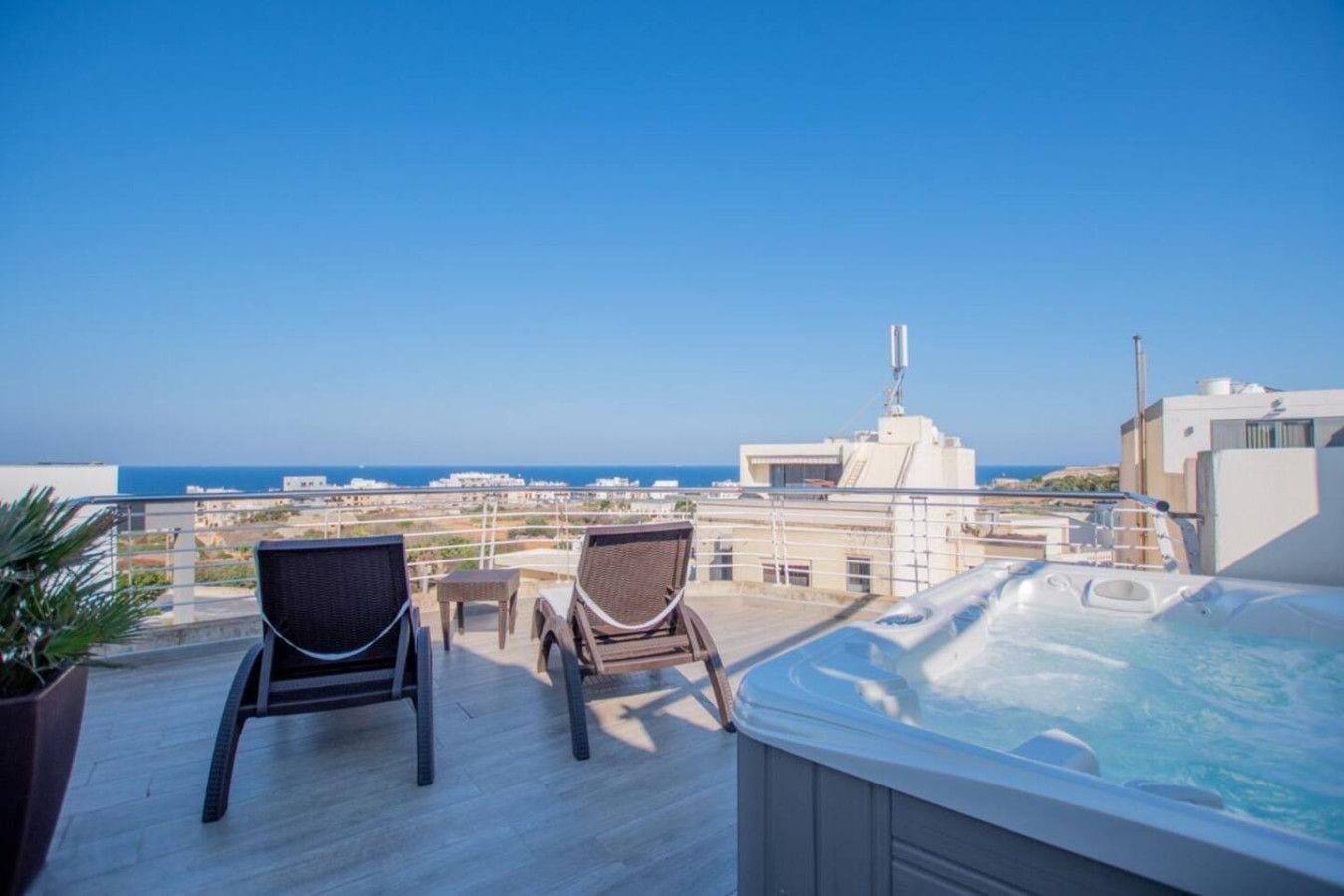 Une terrasse sur le toit avec deux fauteuils en osier, une petite table et un jacuzzi.