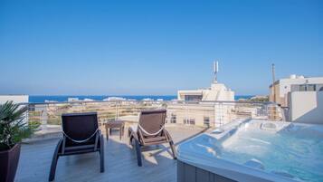 Une terrasse sur le toit avec deux fauteuils en osier, une petite table et un jacuzzi.