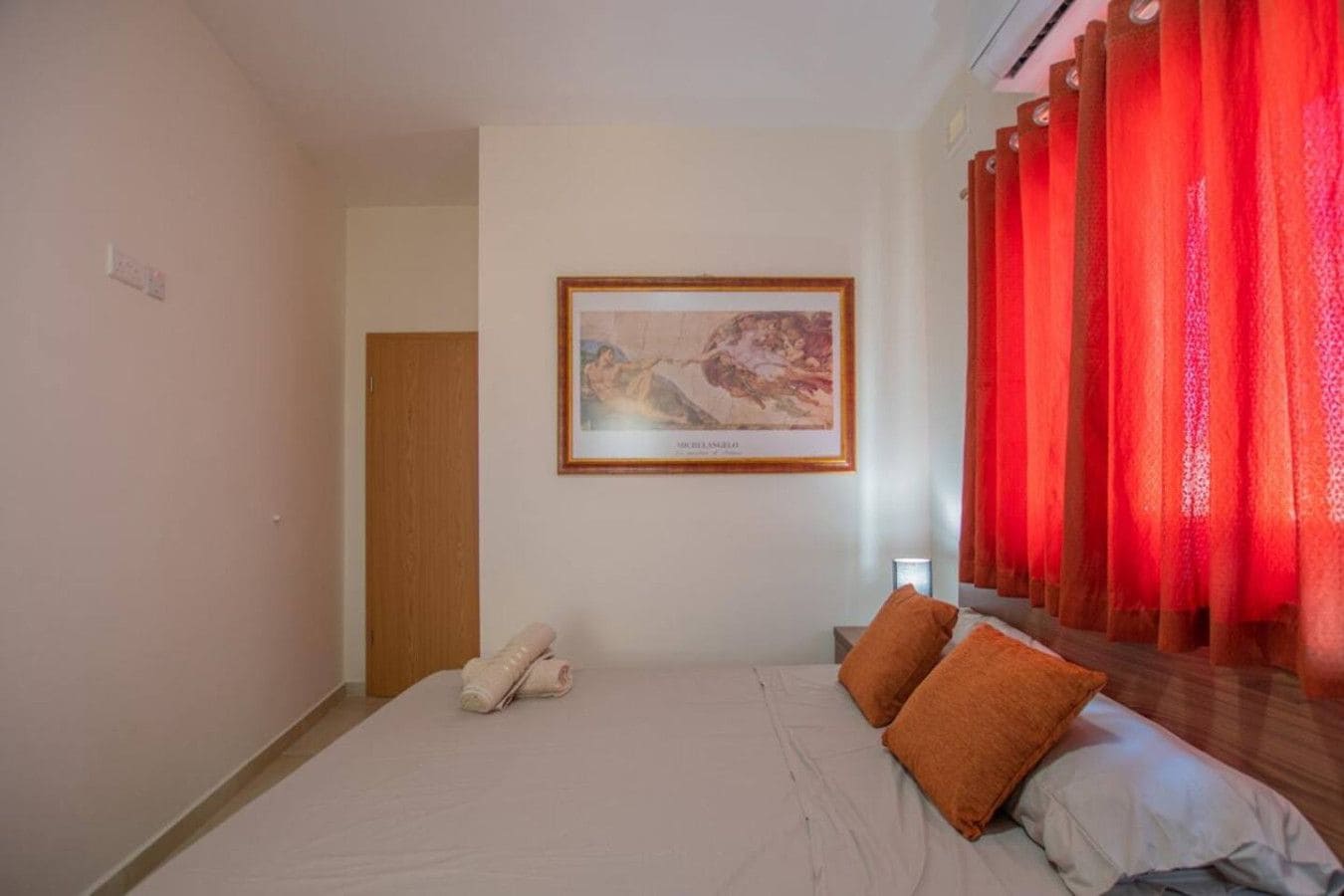A bedroom with a bed, pillows, a painting, and a door.