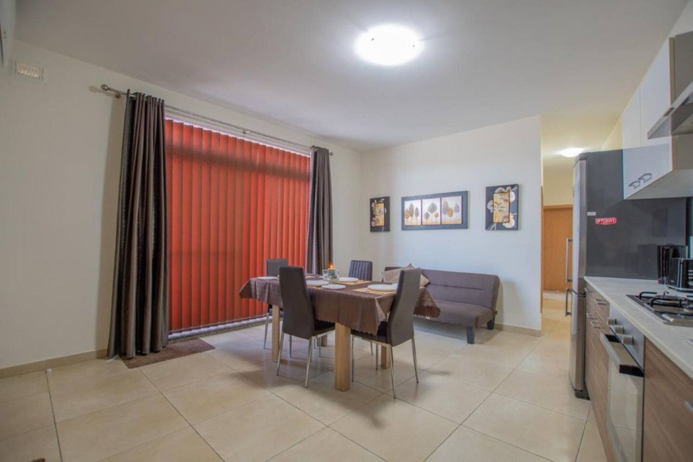Een eetgedeelte met een tafel en stoelen, een bank en een keuken met een fornuis.