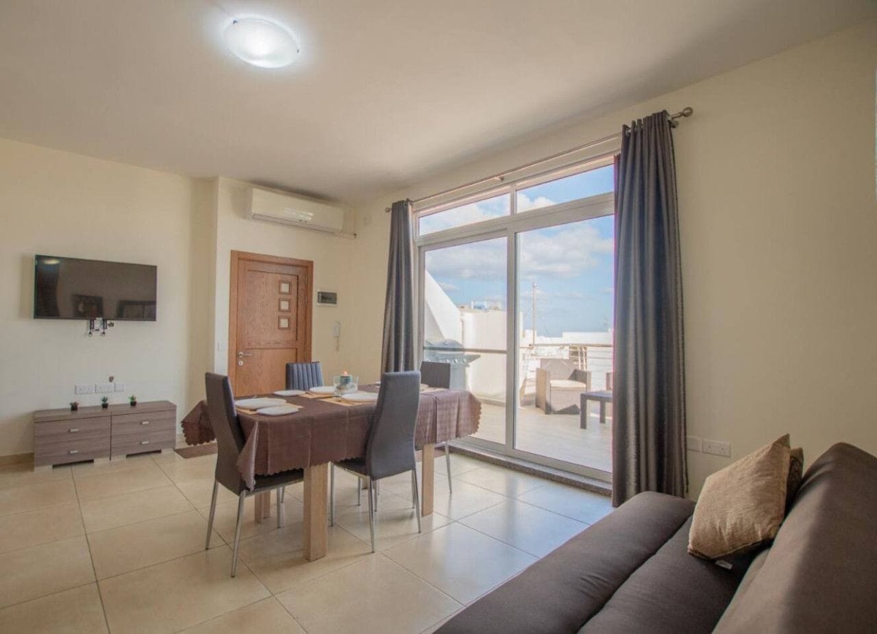 A modern living room with a dining area, a sofa, a flat-screen TV, and a large window with curtains.