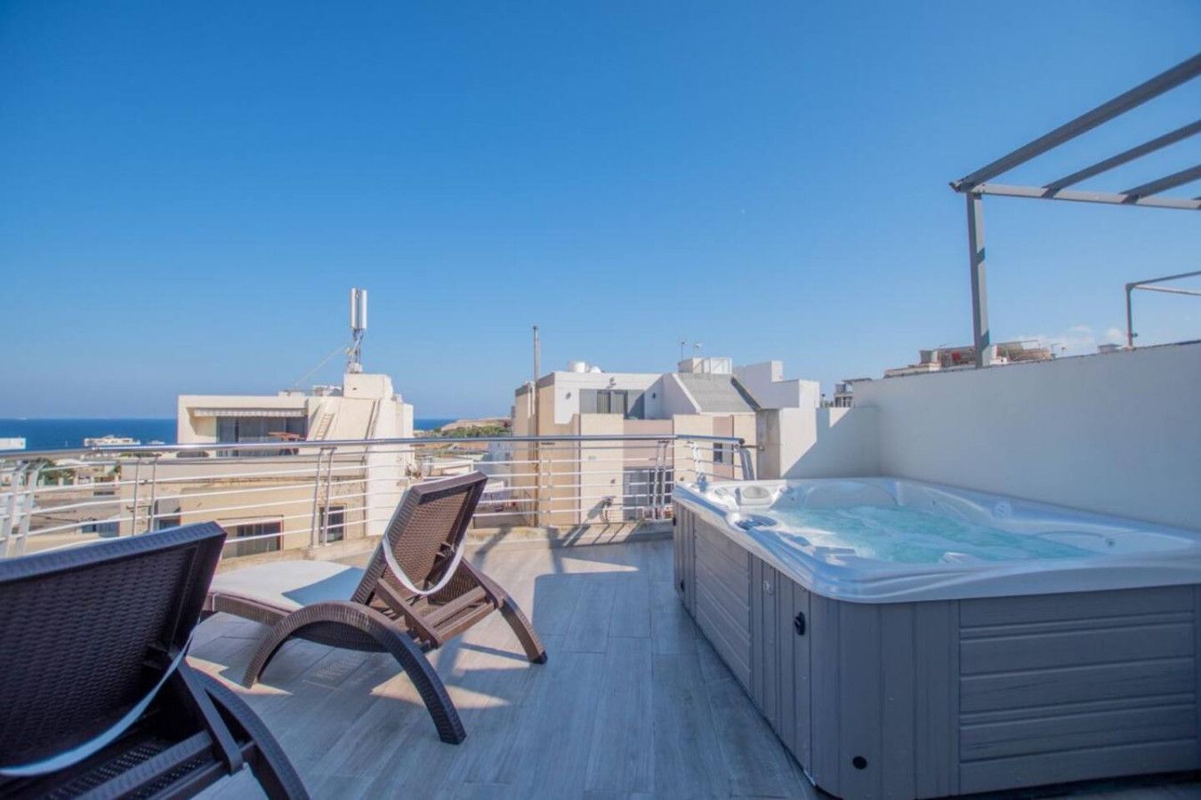 Terraço no telhado com hidromassagem, área de estar e vista para o mar e edifícios.