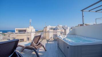 Terraço no telhado com hidromassagem, área de estar e vista para o mar e edifícios.