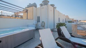 A rooftop terrace with a hot tub, lounge chairs, and water tanks. - The Terrace apartment (Xgħajra)