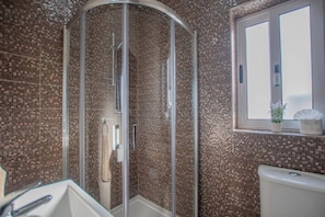 Ein Badezimmer mit einer Duschkabine, einem Waschbecken und einem Fenster mit einer Pflanze.