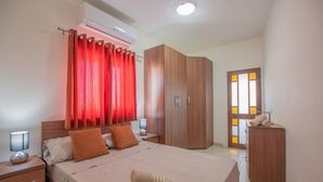 A hotel room with a bed, a wardrobe, a nightstand, a lamp, and a bathroom door. - The Terrace apartment (Xgħajra)