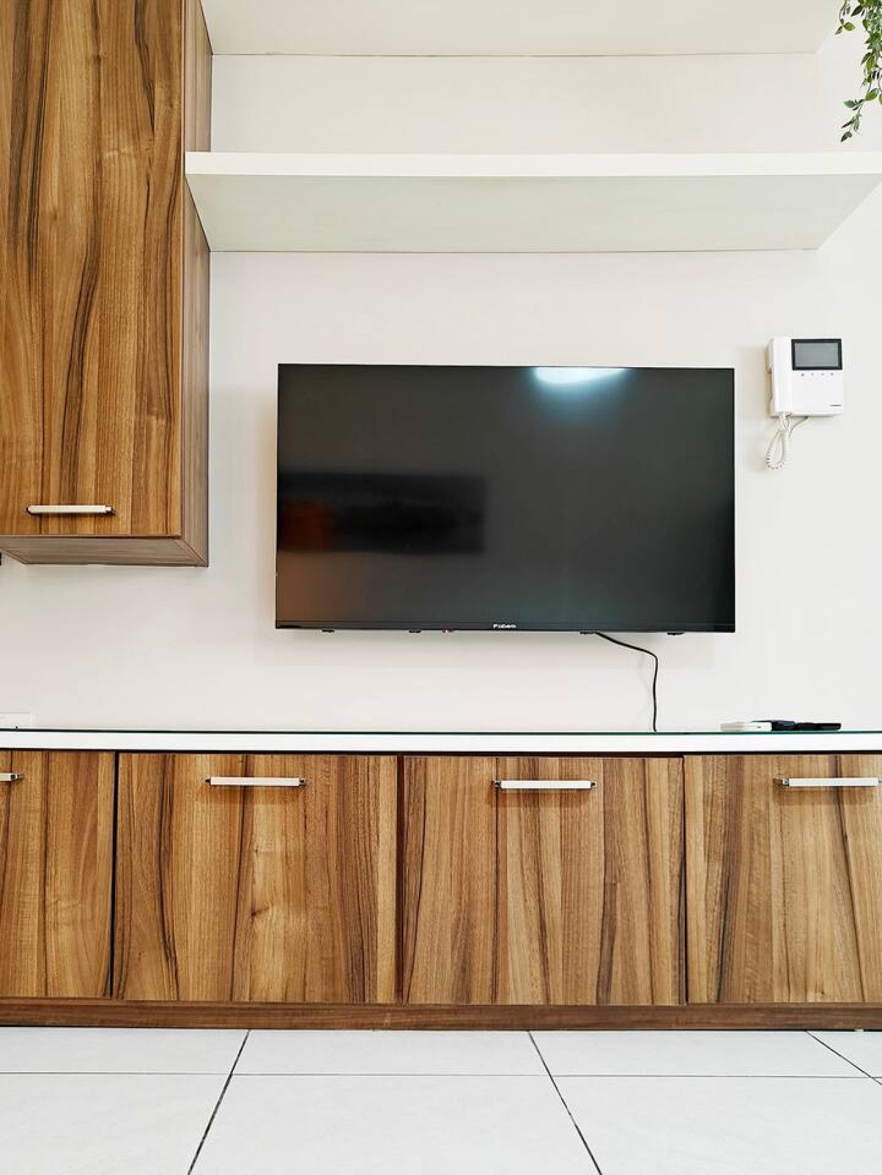 Ein Flachbildfernseher an einer weißen Wand, über einem Holzschrank mit Schubladen.