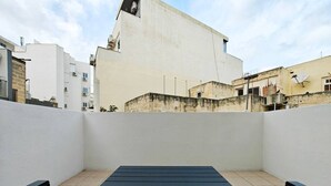 Terraza en la azotea con mesa y sillas, rodeada de edificios.