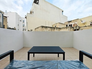 Eine Dachterrasse mit Tisch und Stühlen, umgeben von Gebäuden.