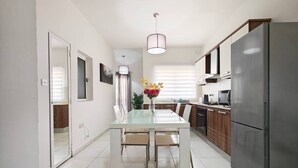 Una cocina moderna con una mesa de comedor de vidrio, electrodomésticos de acero inoxidable y una lámpara colgante.