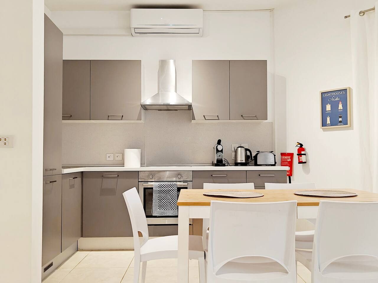 A modern kitchen with stainless steel appliances, a wooden dining table, and white chairs.