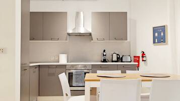 A modern kitchen with stainless steel appliances, a wooden dining table, and white chairs.