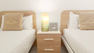 A hotel room with two beds, a bedside table with drawers, and a lamp.