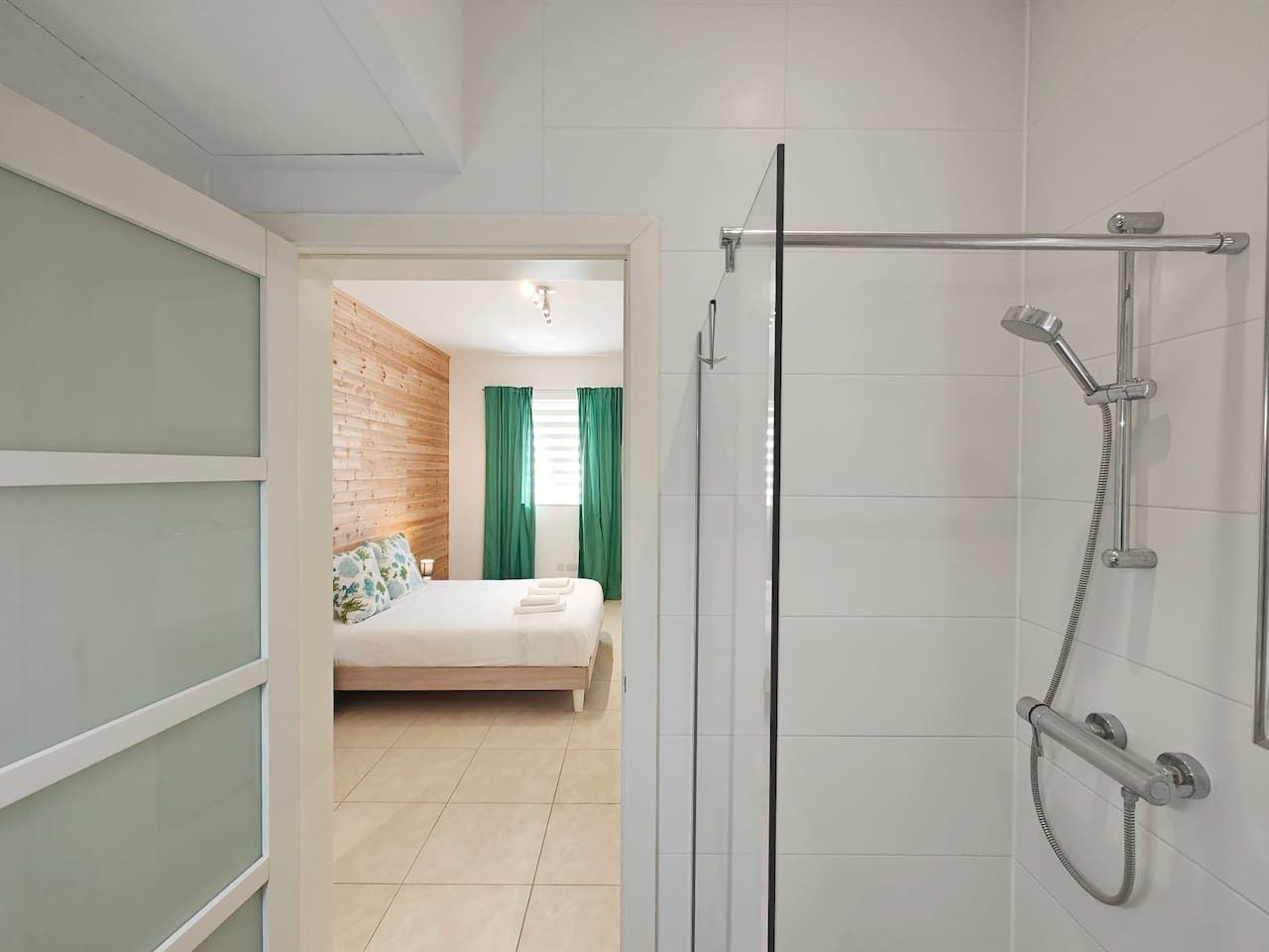 Un baño moderno con cabina de ducha de vidrio, ducha visible y perchero para toallas.