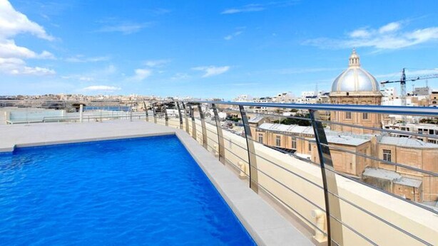 Una piscina en la azotea con vistas despejadas a un edificio con cúpula al fondo.