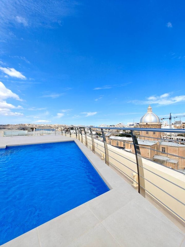 Ein Pool auf dem Dach mit Blick auf ein Kuppelgebäude im Hintergrund.