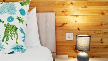 A neatly made bed with a white comforter and a pillow with a marine life print.