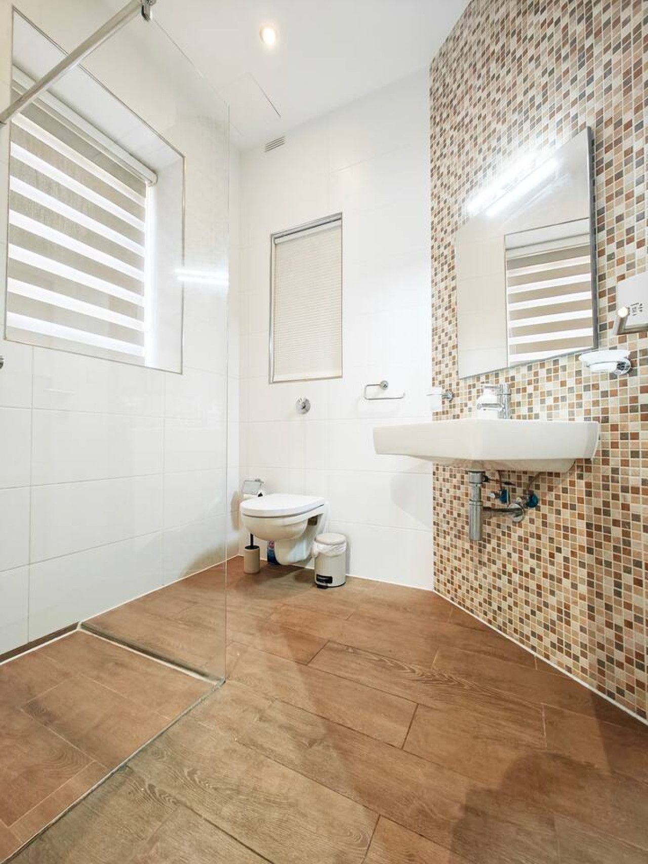 A bathroom with a toilet, sink, and shower area.