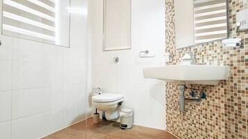 A bathroom with a toilet, sink, and shower area.