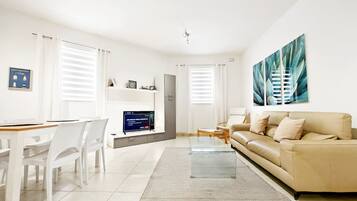 A modern living room with a sofa, a coffee table, and a TV.