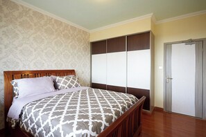 Een slaapkamer met een houten bed, beddengoed met een patroon, een kledingkast met schuifdeuren en een deur met een handvat.