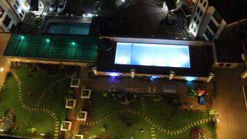 Vista aérea de un hotel con piscina, jardines ajardinados y una entrada bien iluminada.