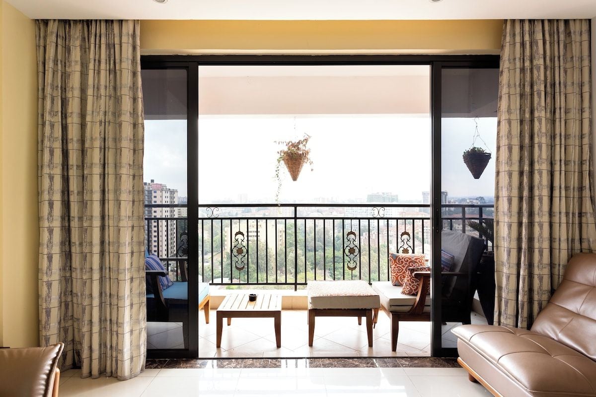 Un salon avec un canapé, une table basse et un balcon offrant une vue sur les immeubles.