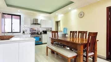 A modern kitchen with white cabinets, a wooden dining table, and a bench.