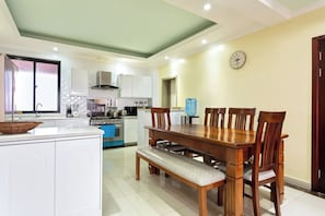 Uma cozinha moderna com armários brancos, uma mesa de jantar de madeira e um banco.