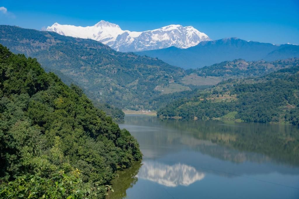Un paysage montagneux avec un lac et, au loin, des sommets enneigés.