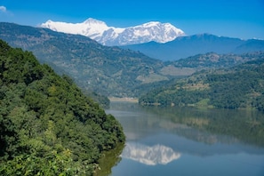 A mountainous landscape with a lake and snow-capped peaks in the distance.