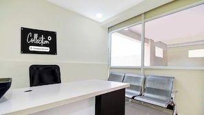 Ein Wartebereich mit einer Rezeption, einem Schild, das es als betriebseigene Abholstelle kennzeichnet, und einem Fenster mit Ausblick.