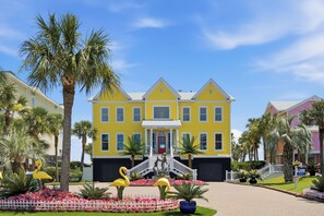 A yellow building with a red door and a staircase leading to the entrance. - Oceanfront home with multiple pools and hot tub (Isle of Palms)
