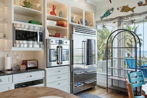 A kitchen with a built-in microwave, oven, and refrigerator. There is a dining area with a table and chairs. - Oceanfront home with multiple pools and hot tub (Isle of Palms)