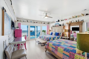 A bedroom with two beds, a desk, a chair, a ceiling fan, and a view of the ocean. - Oceanfront home with multiple pools and hot tub (Isle of Palms)