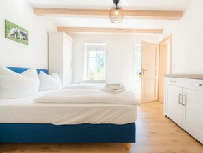 A bedroom with a bed, a window, and a door leading to another room. - Holiday Apartment 2 "hooge" (Tating)