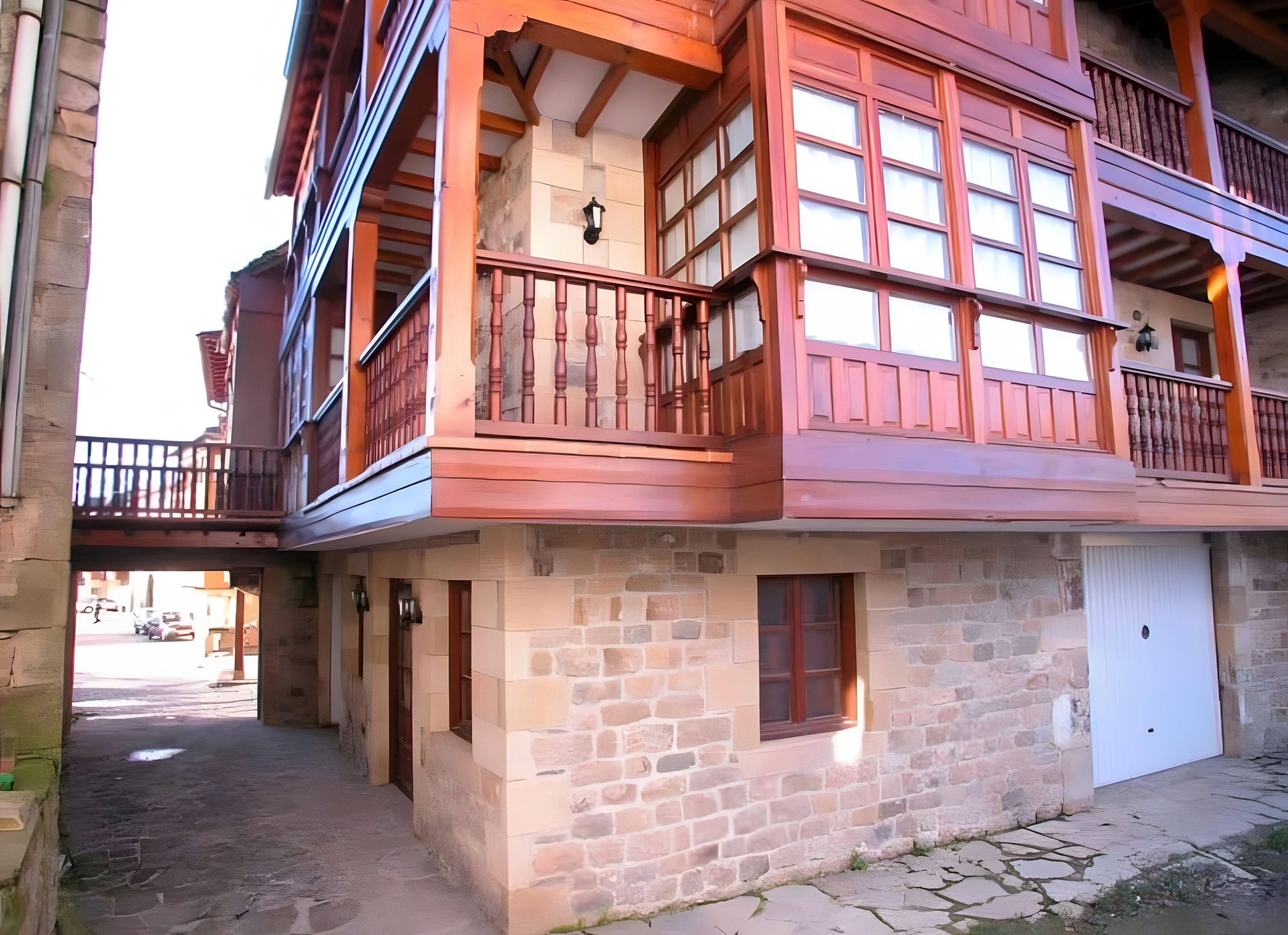A multi-story building with a stone facade, wooden balconies, and a garage door.