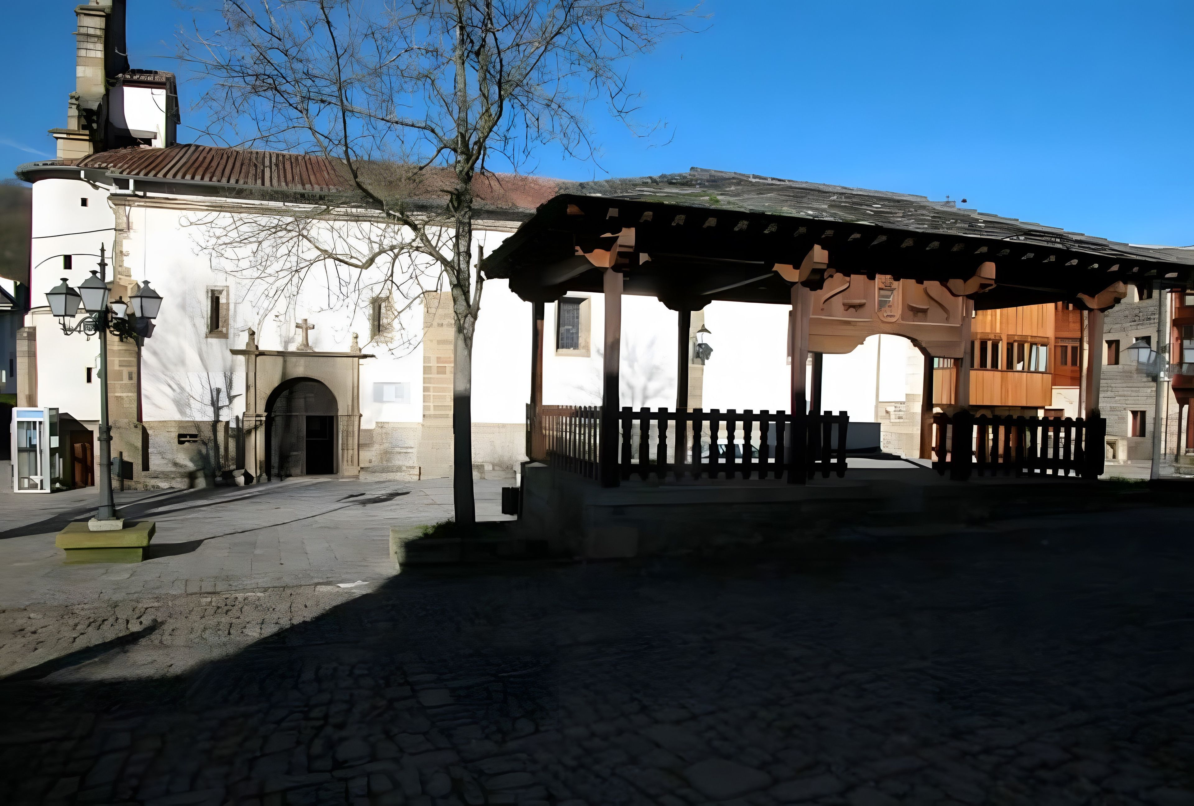 Eine Kopfsteinpflasterstraße mit einem traditionellen Gebäude, das einen überdachten Gang und einen Glockenturm zeigt.